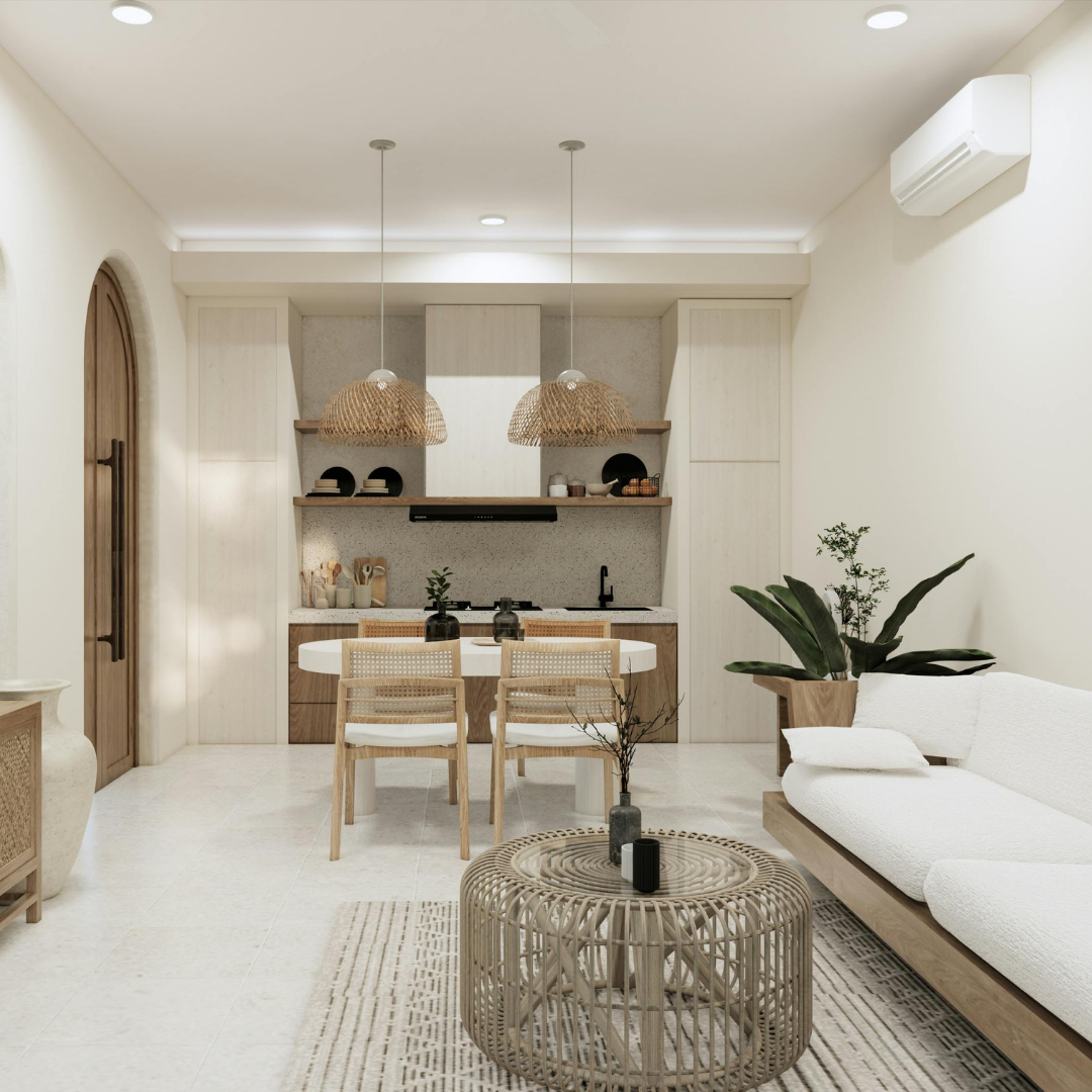 A modern, neutral-toned living room and kitchen with rattan accents, a white sofa, a round coffee table, two pendant lights, and indoor plants. The space features minimal, natural decor and soft lighting.